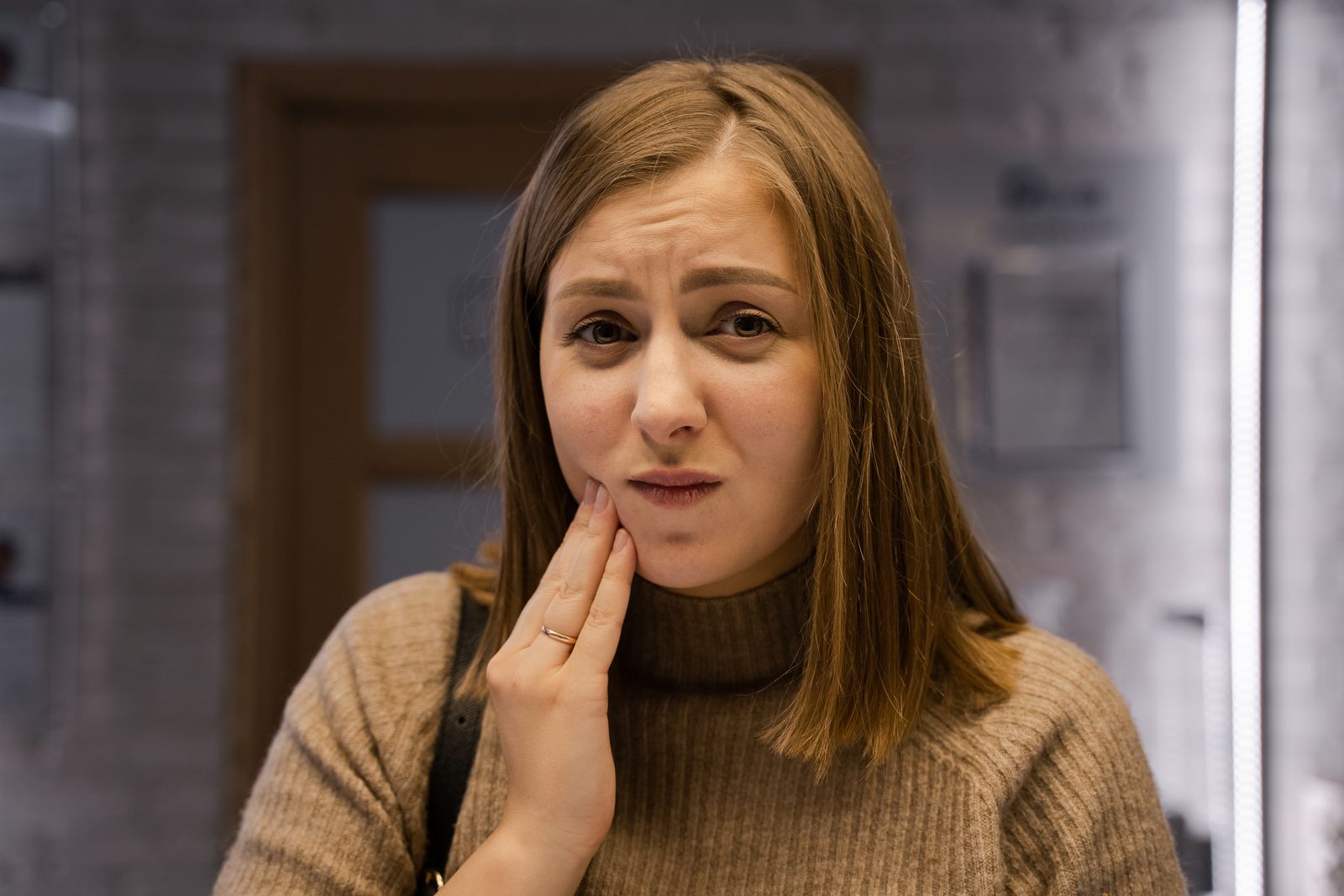Woman holding her jaw because of jaw pain