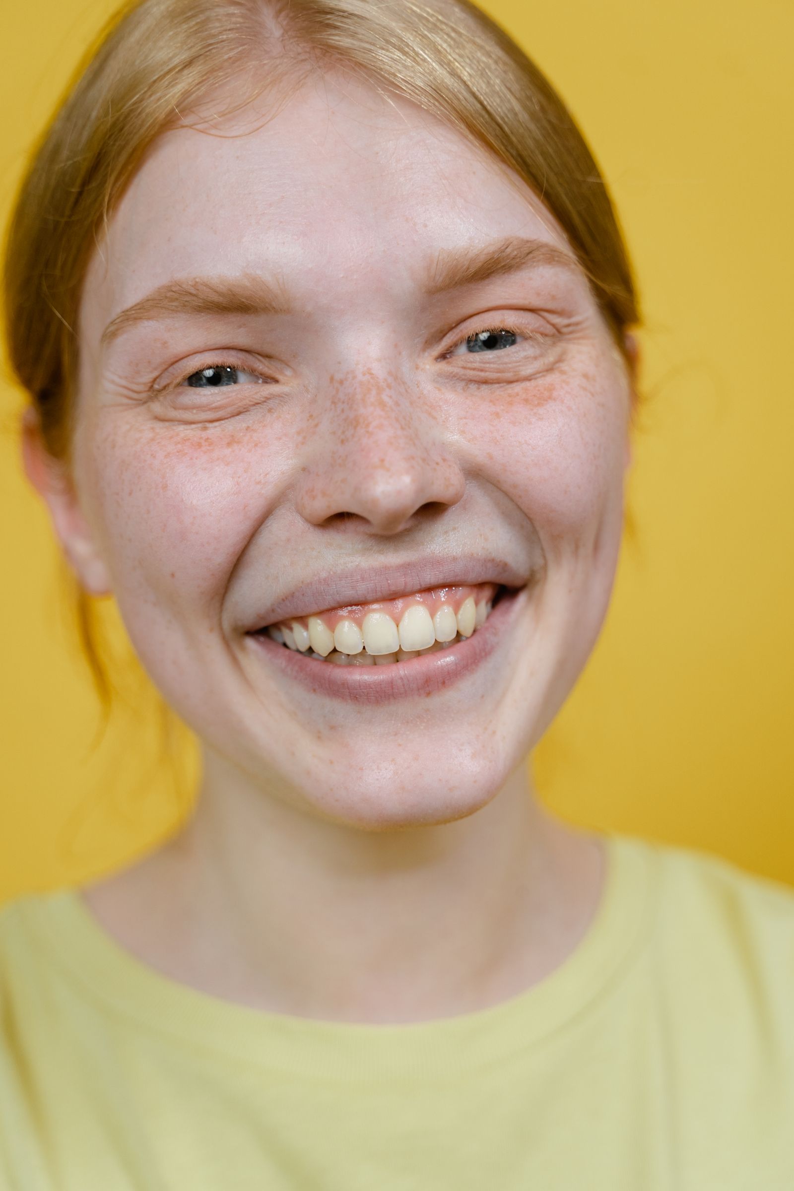 Woman smiling warmly against a yellow background